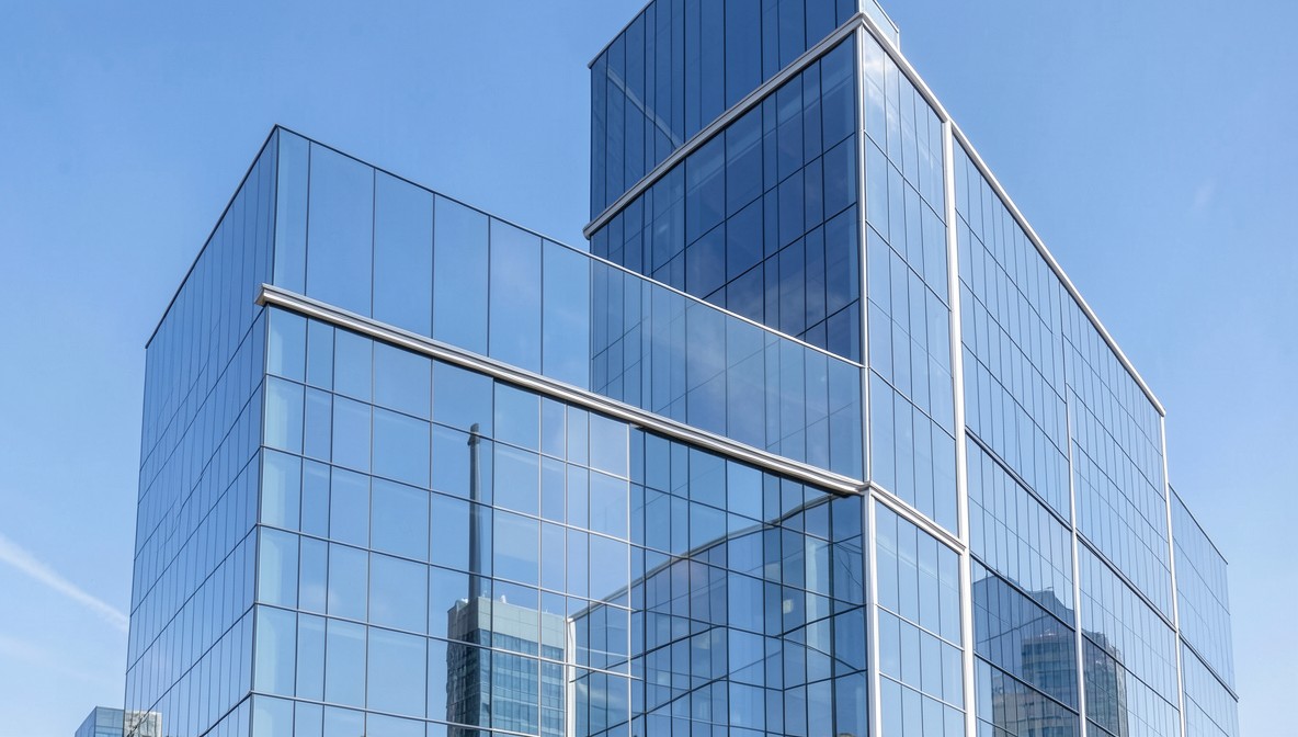 Modern glass office building exterior against a blue sky, representing the workplace where salary negotiations happen